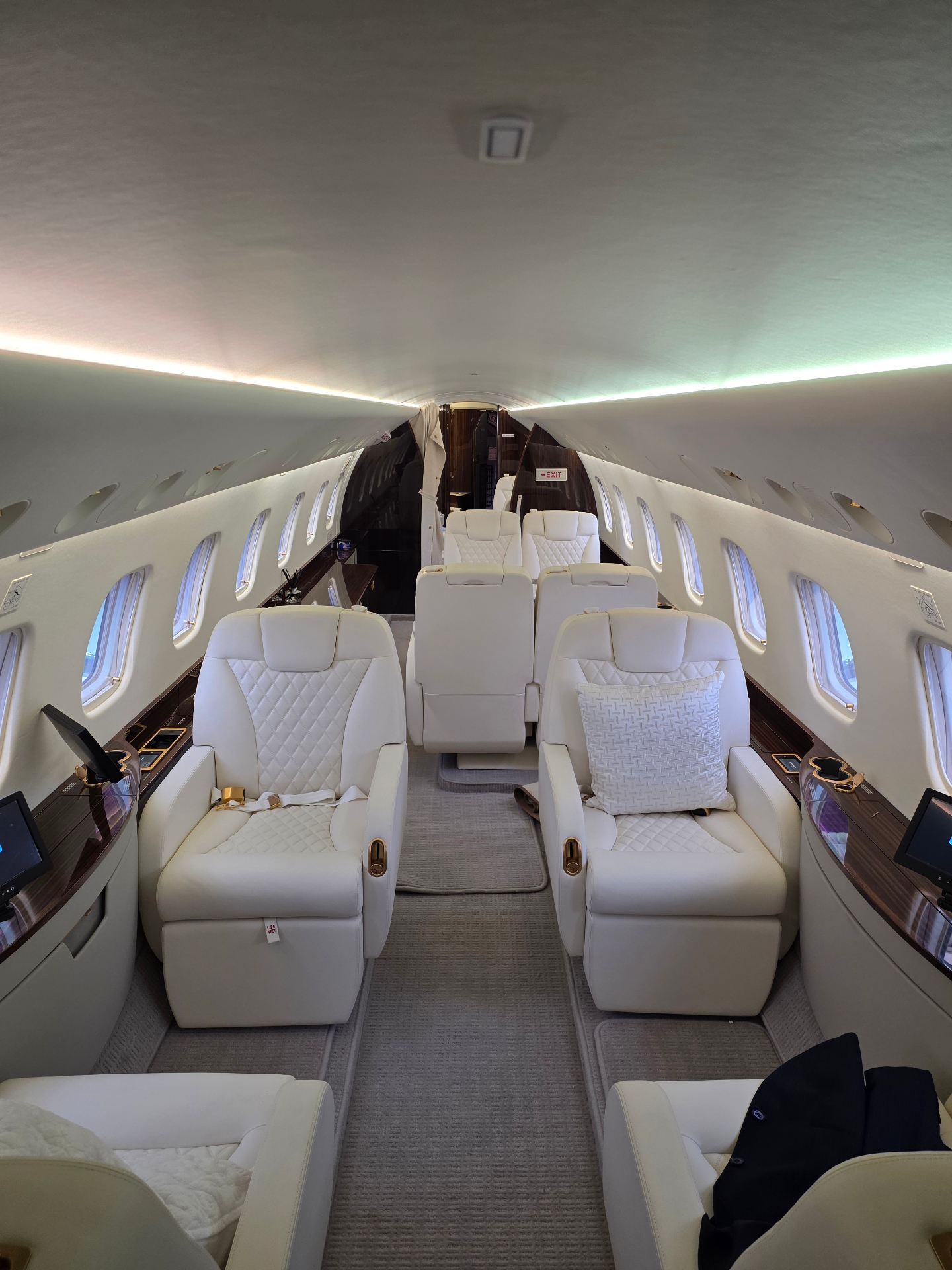Embraer Legacy 650 main cabin with white leather club seating and wood veneer trim